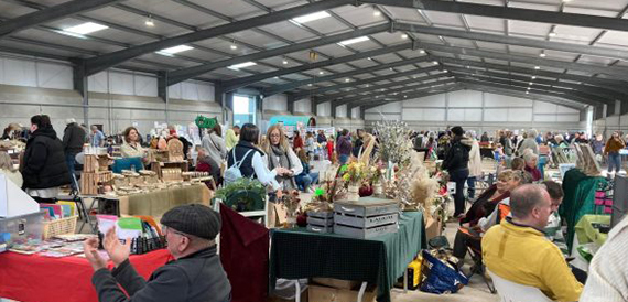 Visitors browsing stalls inside a busy indoor market hall.