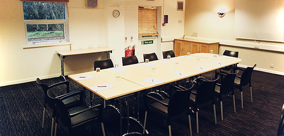 Boardroom table with black chairs set out for a meeting.