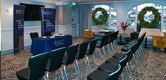 Rows of chairs facing a lectern in a seminar room with a wreath display.