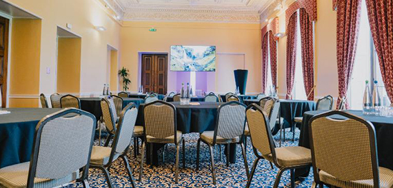 Cabaret-style meeting room with round tables and a wall-mounted screen