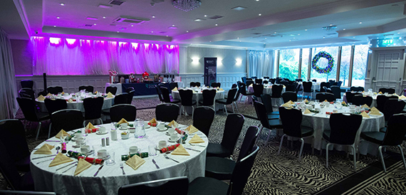 Round dinner tables with black chair covers set for an awards banquet.
