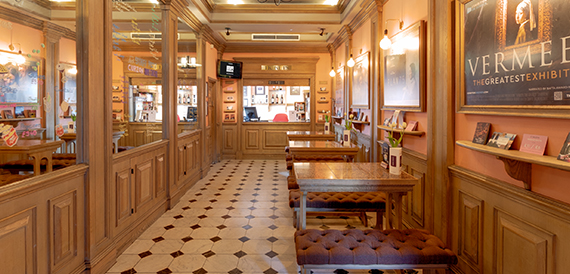 Wood-panelled cafe with a chequered floor and wooden tables