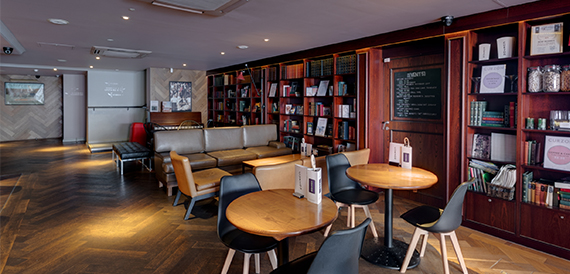 Lounge with bookshelves, round wooden tables and mismatched chairs