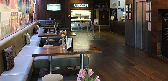 Cafe area with wooden tables and a view toward the Curzon bar