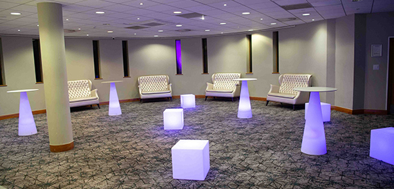 Lounge area with illuminated cube seats and purple-lit high tables.