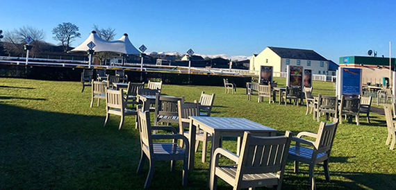 Outdoor garden seating with tables beside a marquee at Carlisle Racecourse