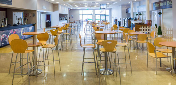 Cafe area with orange chairs and high tables