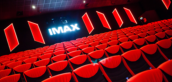 IMAX auditorium screen wall lit with red neon panels above empty seating
