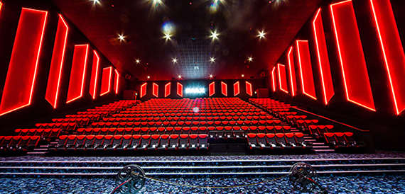 Wide view of an IMAX auditorium with red seating and neon-lit side panels