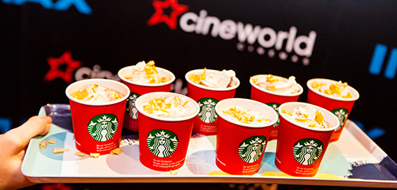 Starbucks cups topped with cream and popcorn on a tray against Cineworld branding