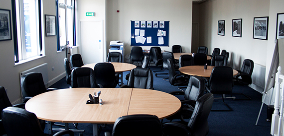 Meeting room with round wooden tables and black leather chairs