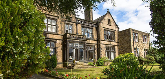 Victorian stone house exterior with a bay window and garden