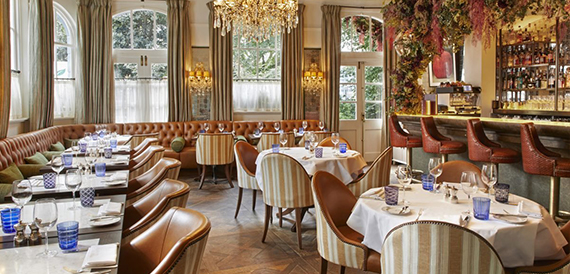 Restaurant dining area with leather booth seating, striped chairs and a crystal chandelier