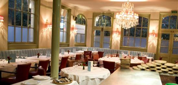Restaurant with white tablecloths, a green column and a crystal chandelier