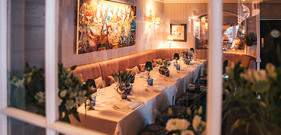 Dining booth beneath a colourful mural with a candlelit table