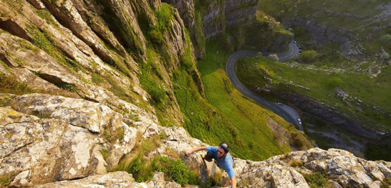Aerial view of Cheddar Gorge's winding road with a climber on the rock face