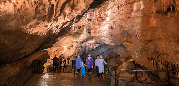 Visitors walking a cave walkway beneath hanging stalactites