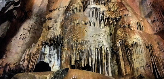 Close-up cave formations of stalactites and stalagmites lit in warm tones