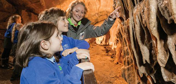 Schoolchildren and a guide pointing out cave formations on a tour