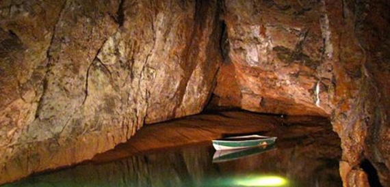 Small rowing boat moored on a still underground lake in the cave