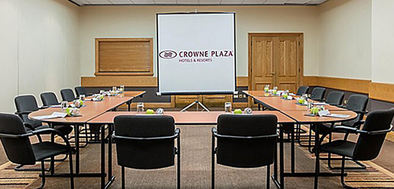 Meeting room set classroom-style with a projector screen showing hotel branding