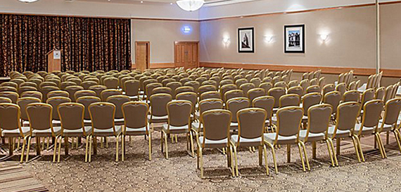 Conference hall set theatre-style with rows of chairs facing a curtained stage