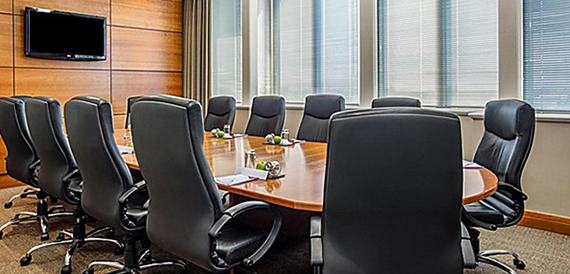 Boardroom with a long table, black leather chairs and blinds at the windows