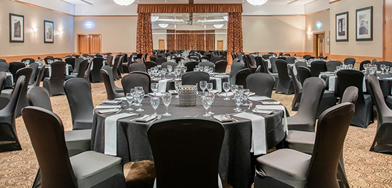 Banqueting room with round tables set with white linen and glassware