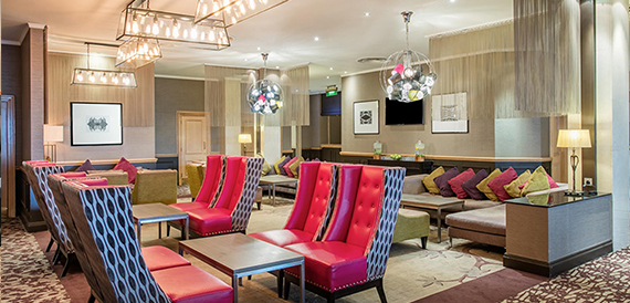 Hotel lounge with pink armchairs, patterned seating and statement chandeliers