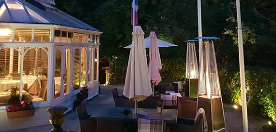 Outdoor terrace at night with patio heaters and folded parasols