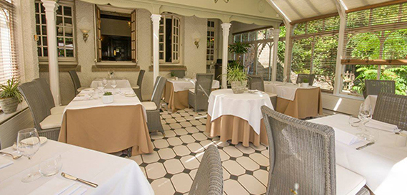 Conservatory dining room with a tiled floor and tables dressed in white linen