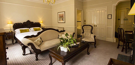 Antique-furnished bedroom with a carved wood sofa and chandelier