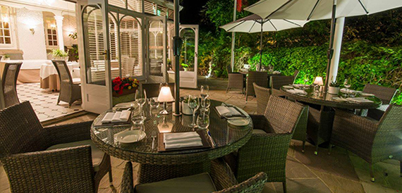 Rattan tables set for dinner on a lantern-lit terrace at night