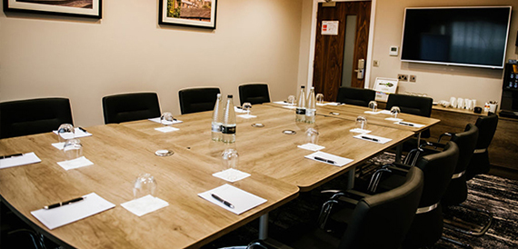 Boardroom with a long wooden table set with water bottles and notepads