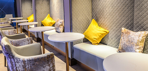 Lounge seating area with a quilted banquette and yellow cushions