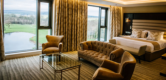 Hotel suite with sofa and armchairs overlooking a lake and golf course