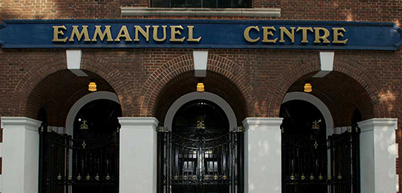 Exterior signage reading Emmanuel Centre above brick arches and iron gates.