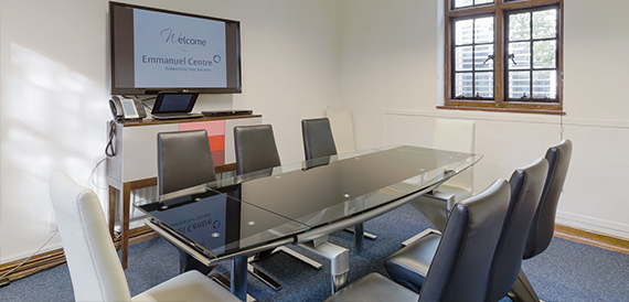 Small boardroom with a glass table, leather chairs and a wall-mounted welcome screen.
