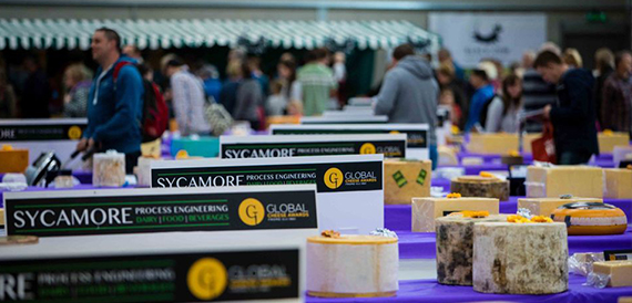 Crowds viewing cheese displays at an indoor food competition.