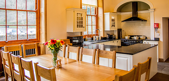 Farmhouse-style kitchen with a wooden dining table, cream cabinetry and a range cooker.