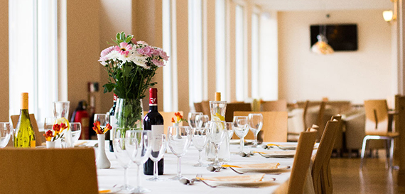 Dining room table close-up with wine bottles, flowers and place settings.