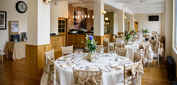 Dining room with round tables in cream linen and hessian chair sashes.