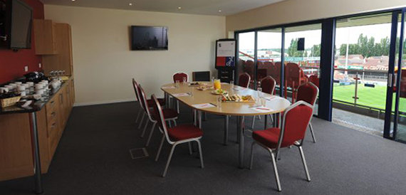 Oval table with red chairs set boardroom-style beside glass doors.