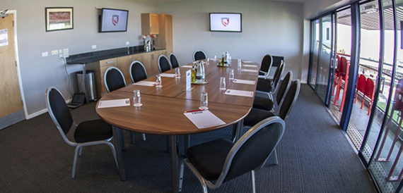 Oval wooden boardroom table with black chairs in a branded meeting room.