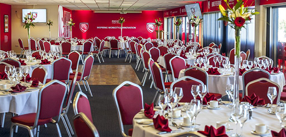 Long dining tables with red napkins and wine glasses set for a banquet.