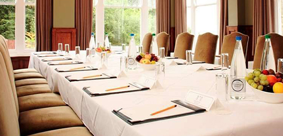 Boardroom table set with tan leather chairs, notepads and bowls of fresh fruit.