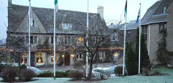 Stone hotel exterior at dusk with flagpoles and string lights along the entrance.