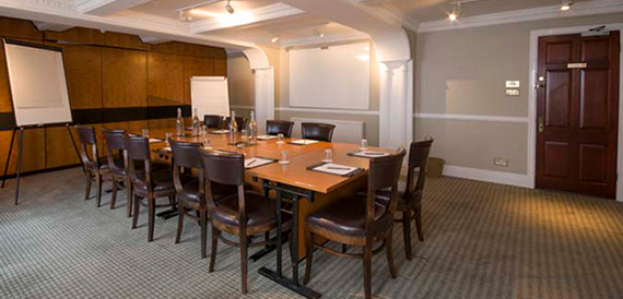 Boardroom with a long table, brown leather chairs and two flipcharts.