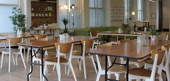 Cafe-style dining area with wooden tables, mismatched chairs and potted plants