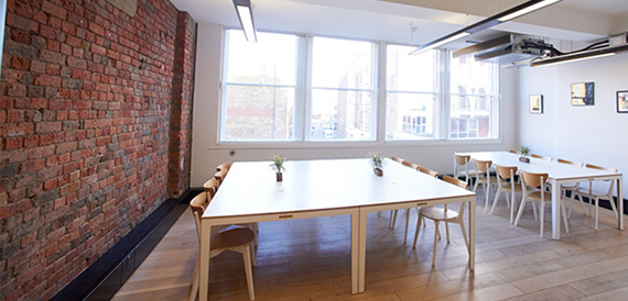 Long meeting table with wooden chairs against an exposed brick wall